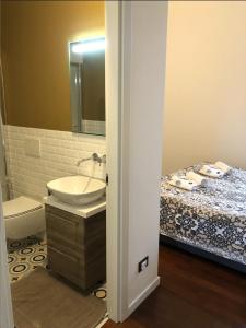 a bathroom with a sink and a toilet and a bed at Camera Albergo - Suites Mansion in Rozzano