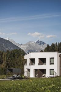 a white house with mountains in the background at Alpinhotel Keil in Valdaora