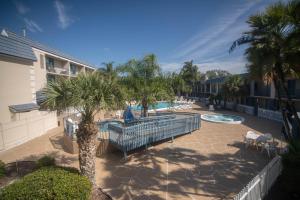 a patio with a swimming pool and palm trees at Clarion Inn & Suites Central Clearwater Beach in Clearwater