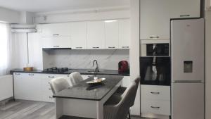 a kitchen with white cabinets and a table and chairs at Apartament in Craiova