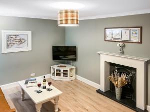 a living room with a table and a fireplace at Rose Cottage in Freuchie