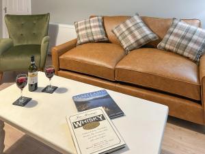 a living room with a couch and a table with wine glasses at Rose Cottage in Freuchie