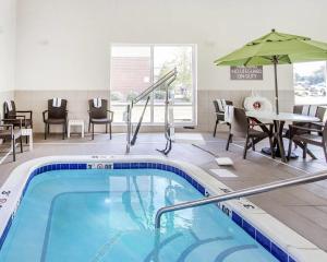 a pool with chairs and a table and an umbrella at Comfort Suites Marietta-Parkersburg in Marietta