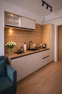 a kitchen with white cabinets and a blue couch at New Corner Apartamenty in Niechorze