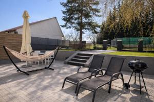 a hammock and chairs on a patio with a grill at New Corner Apartamenty in Niechorze