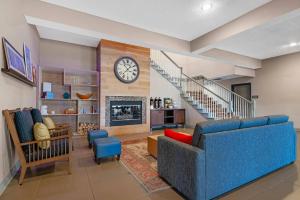 a living room with a blue couch and a clock at Country Inn & Suites by Radisson, West Bend, WI in West Bend