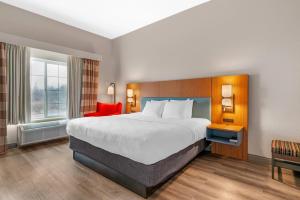 a hotel room with a large bed and a red chair at Country Inn & Suites by Radisson, West Bend, WI in West Bend +33 photos