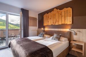 a bedroom with a large bed and a balcony at Fairhotel Hochfilzen B&B in Hochfilzen