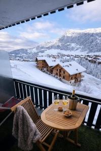 a table with two glasses of wine on a balcony at Lodge Montëva - Le Chinaillon - Au pied des pistes in Le Grand-Bornand