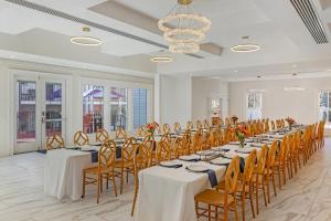 a banquet hall with tables and chairs and a chandelier at The Colonial Inn, an Ascend Collection Hotel in Hillsborough
