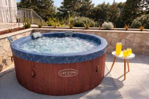a large wooden hot tub with a table and drinks at Holiday Home Lungo Mare in Mlini