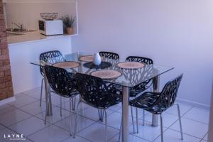 a glass dining table with black chairs in a kitchen at Kabi Apartment Caloundra - Self Contained in Golden Beach