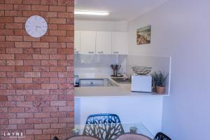 a kitchen with a brick wall and a clock on a wall at Kabi Apartment Caloundra - Self Contained in Golden Beach