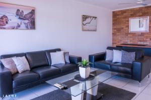 a living room with a black leather couch and a table at Kabi Apartment Caloundra - Self Contained in Golden Beach