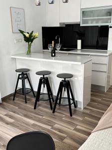 a kitchen with a white counter and two bar stools at Studio Apartman Fictilis in Split +16 photos