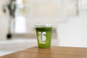 a green drink in a plastic cup sitting on a table at Grood Glamping in Ban Khok Sung