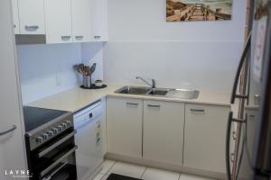 a small kitchen with white cabinets and a sink at Kabi Apartment Caloundra - Self Contained in Golden Beach +10 photos