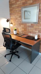 a desk with a laptop and a chair in front of a brick wall at Kabi Apartment Caloundra - Self Contained in Golden Beach