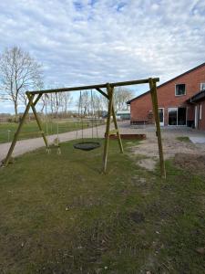 a wooden swing set in a field of grass at Højmosegård værelse 1 in Varde
