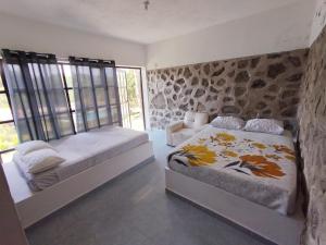 a bedroom with two beds and a stone wall at La gloria hospedajes in Cuernavaca +26 photos