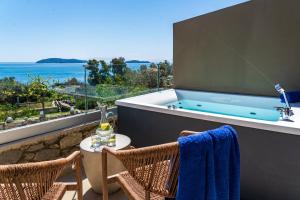 a bathroom with a tub and two chairs and a table at Irida Aegean View, Philian Hotels and Resorts in Megali Ammos