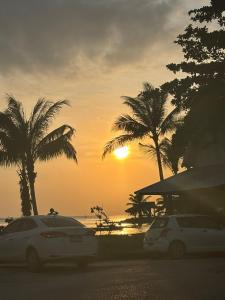 two cars parked in front of a beach with palm trees at blissful well treat in Ban Madua Wan