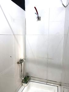 a white tiled bathroom with a shower and a toilet at Cocon lumineux tout équipé in Dzaoudzi