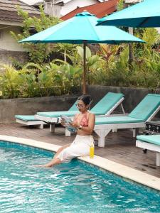 a woman sitting in the water next to a swimming pool at Lantis Corp Inn in Sengkol