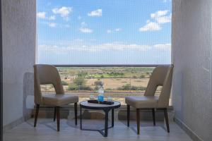 a room with two chairs and a table and a window at King's Kraft Shubh Hotel in Dwarka