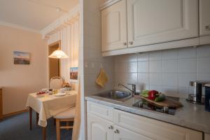 a kitchen with white cabinets and a sink and a table at Kim im Haus Wega in Westerland +10 photos