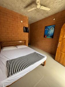 a bed in a room with a brick wall at Auro Waves Rooms & Hostel in Auroville +5 photos