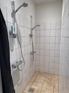 a shower in a bathroom with a tiled wall at Højmosegård værelse 1 in Varde +25 photos