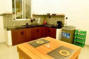 a kitchen with a wooden table and a sink at Abey Villa Madiha Beach Surf Stay in Matara