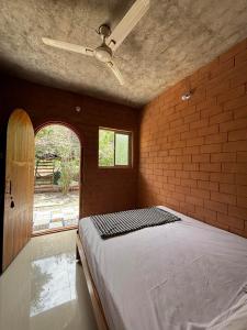 a bedroom with a bed in a brick wall at Auro Waves Rooms & Hostel in Auroville