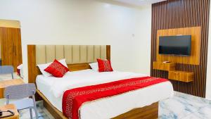 a bedroom with a bed with red pillows and a tv at Hotel PR Royal in Bhīmavaram