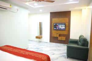a living room with a couch and a tv on a wall at Hotel PR Royal in Bhīmavaram
