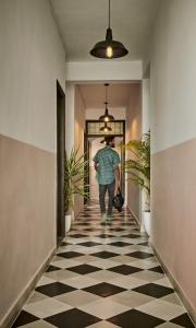 a man walking down a hallway with a checkered floor at Minimalist Poshtel & Suites in New Delhi