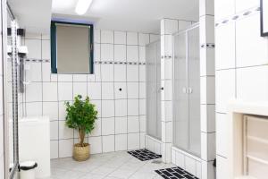 ein Badezimmer mit weiß gefliesten Wänden und einer Topfpflanze in der Unterkunft Hostel LR in Nazarje + 15 Fotos