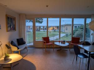 a living room with chairs and tables and windows at Djurs-BnB - Rimsøhuset in Rimsø