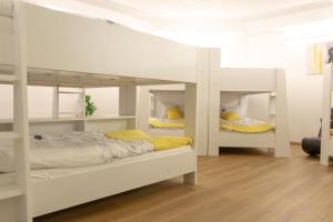 ein Schlafzimmer mit zwei weißen Etagenbetten und gelben Kissen in der Unterkunft Hostel LR in Nazarje