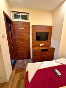 a bedroom with a bed and a television and a wooden door at Hotel Ashirwad Inn in Mumbai