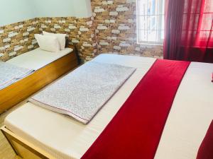 two beds in a room with red and white sheets at Global hotel in Pānigata