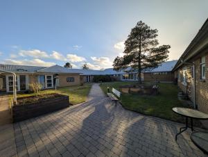 a patio with two tables and a tree and a building at Djurs-BnB - Rimsøhuset in Rimsø