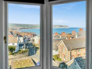 a window with a view of a city and the ocean at Flat 4 Sea Court in Swanage