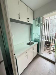 a kitchen with white cabinets and a sink and a window at Regenthome 28A in Bang Su