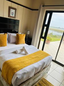 a bedroom with a large bed with a large window at River Front Guest House in Gqeberha