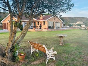 a wooden bench sitting in a yard next to a tree at River Front Guest House in Gqeberha