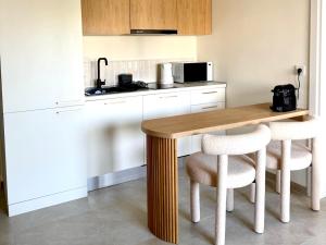 a kitchen with a wooden table and two white chairs at Covea by the Sea Boho Seaside Apartment, 400 m from the Beach in Perea