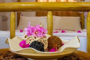 a bowl filled with chocolate and flowers on a bed at Mbao Boutique Bungalows in Jambiani