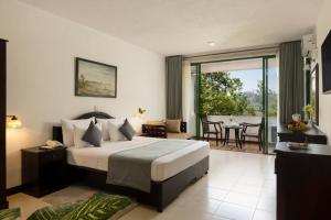 a bedroom with a bed and a balcony with a table at Tree of Life Nature Resort in Kandy